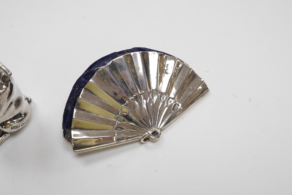 A George V silver mounted fan pin cushion, Henry Matthews, Birmingham, 1912, width 62mm, together with an Edwardian silver vesta case and a white metal pig vesta case.